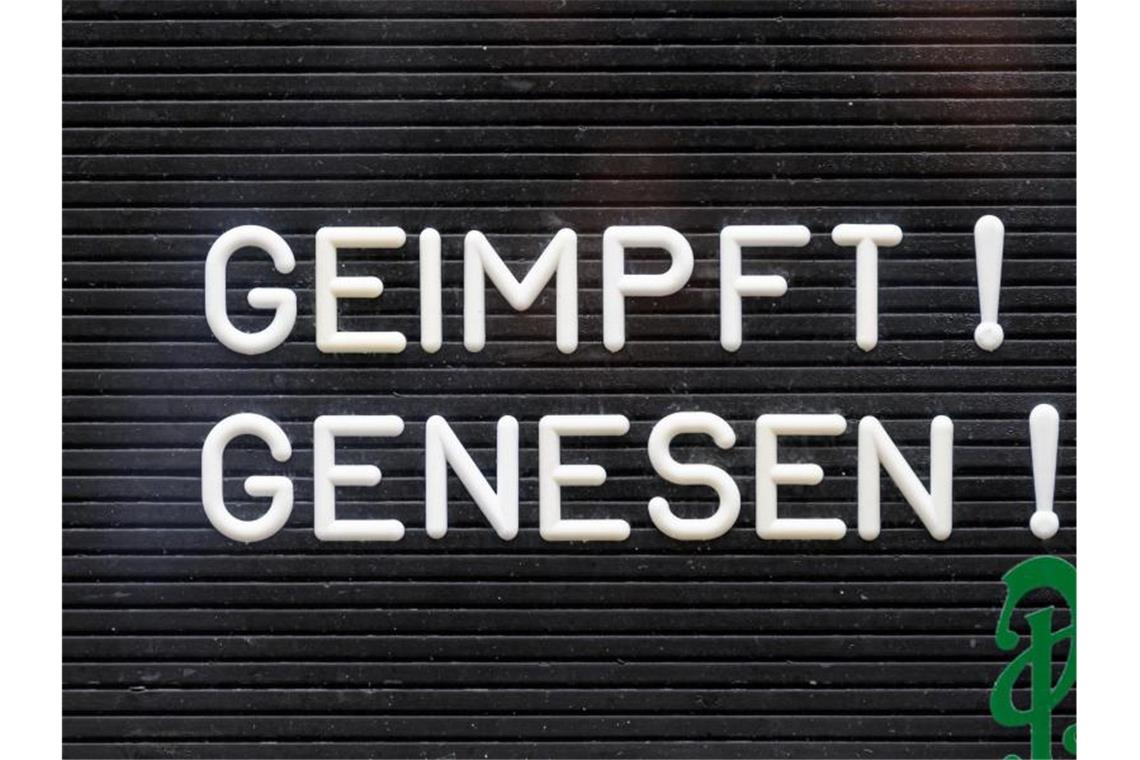 "Geimpft! Genesen!" steht auf einem Schild an einer Bar. Foto: Robert Michael/dpa-Zentralbild/dpa/Symbolbild