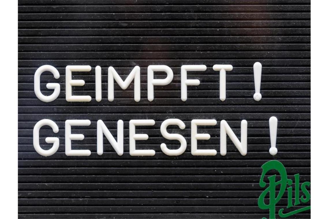 „Geimpft! Genesen!“ steht auf einem Schild. Foto: Robert Michael/dpa-Zentralbild/dpa/Symbolbild