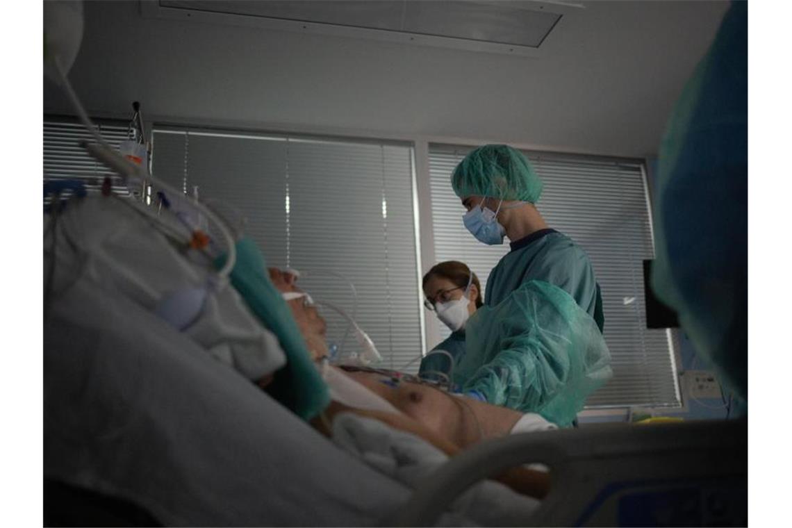 Corona in Europa: Verschärfte Maßnahmen und Massentests Gesundheitspersonal behandelt auf der Intensivstation eines Krankenhauses in Spanien einen Patienten. Foto: David Zorrakino/EUROPA PRESS/dpa