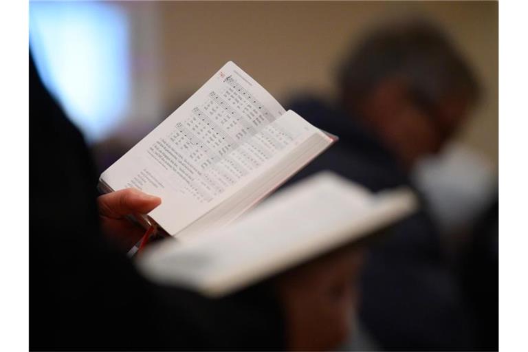 Gläubige singen während eines Gottesdienstes aus dem Liederbuch. Foto: Sebastian Gollnow/dpa/Symbolbild/Archivbild