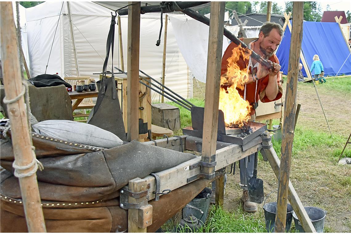 Handarbeit: Hannes, der Schmied, facht das Feuer mit einem großen Blasebalk an, ...