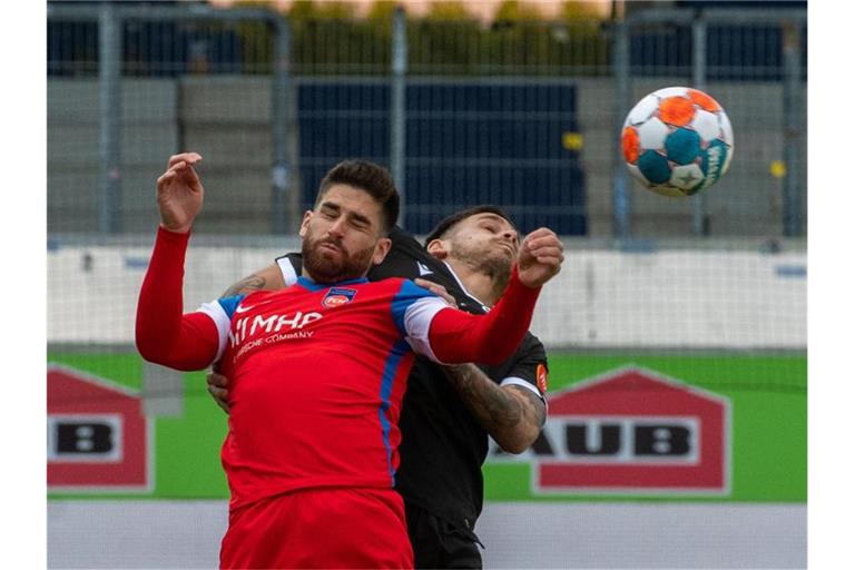 Heidemheims Stefan Schimmer (l) und Sandhausens Dario Dumic sind im Kopfballduell. Foto: Stefan Puchner/dpa