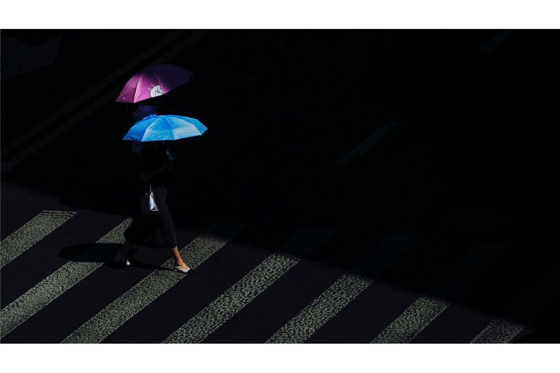 Hitzewelle in China: Fußgänger schützen sich mit Regenschirmen vor der Sonne an einem ungewöhnlich heißen Tag.