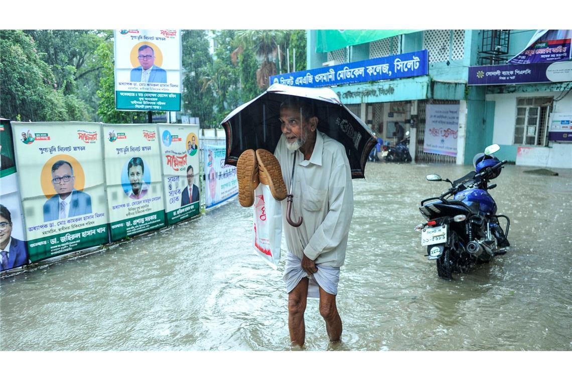 Hochwasser in Bangladesch: Um zum Krankenhaus zu gelangen, muss ein Patient durch Wassermassen waten. Aufgrund anhaltender Regenfälle sind die Straßen in Sylhet überflutet worden.