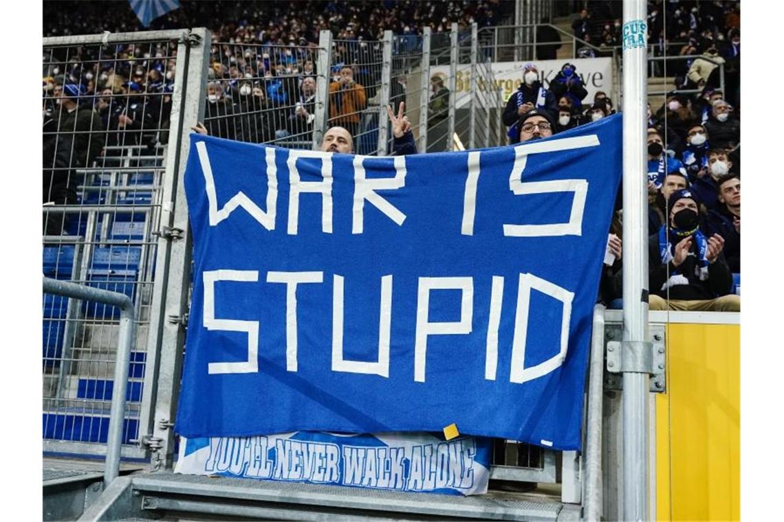 Hoffenheimer Fans halten ein Transparent mit der englischen Aufschrift „War ist stupid“ in den Händen. Foto: Uwe Anspach/dpa