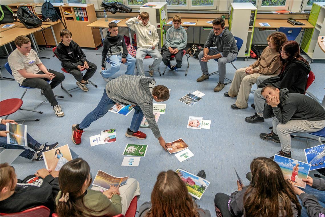 Im Kurs „Glück und Lebenszufriedenheit“ mit Konrektor Kai Kasper (hinten rechts) sprechen die Schülerinnen und Schüler über ihre Lebensziele. Sie haben sich dazu aus einem größeren Fundus für sie passende Bilder ausgesucht. Foto: Stefan Bossow