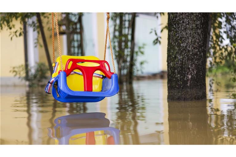 Im niederösterreichischen Ort Kapelln hängt eine Kinderschaukel knapp über dem braunen Hochwasser in einem Garten.