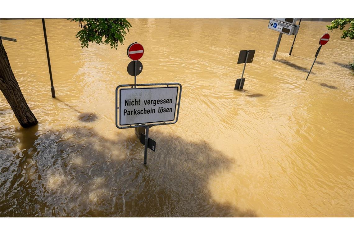 In Bayern herrscht nach heftigen Regenfällen vielerorts weiter Hochwasser. Ein Schild mit der Aufschrift „Nicht vergessen, Parkschein lösen“ in Passau deutet auf einer überfluteten Parkplatz hin.