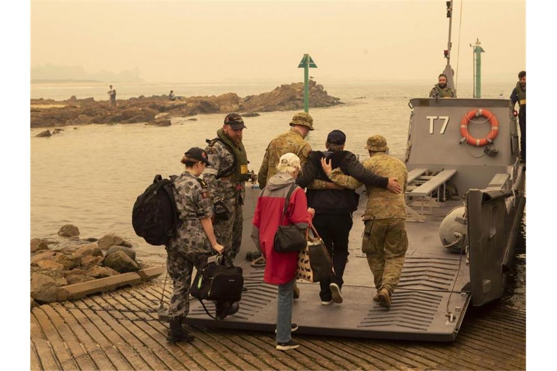 Tausende fliehen vor Feuern in Australien In der Küstenstadt Mallacoota bringt die Marine Menschen in Sicherheit, die sich an den Strand gerettet hatten. Foto: Pois Helen Frank/Royal Australian Navy/AP/dpa