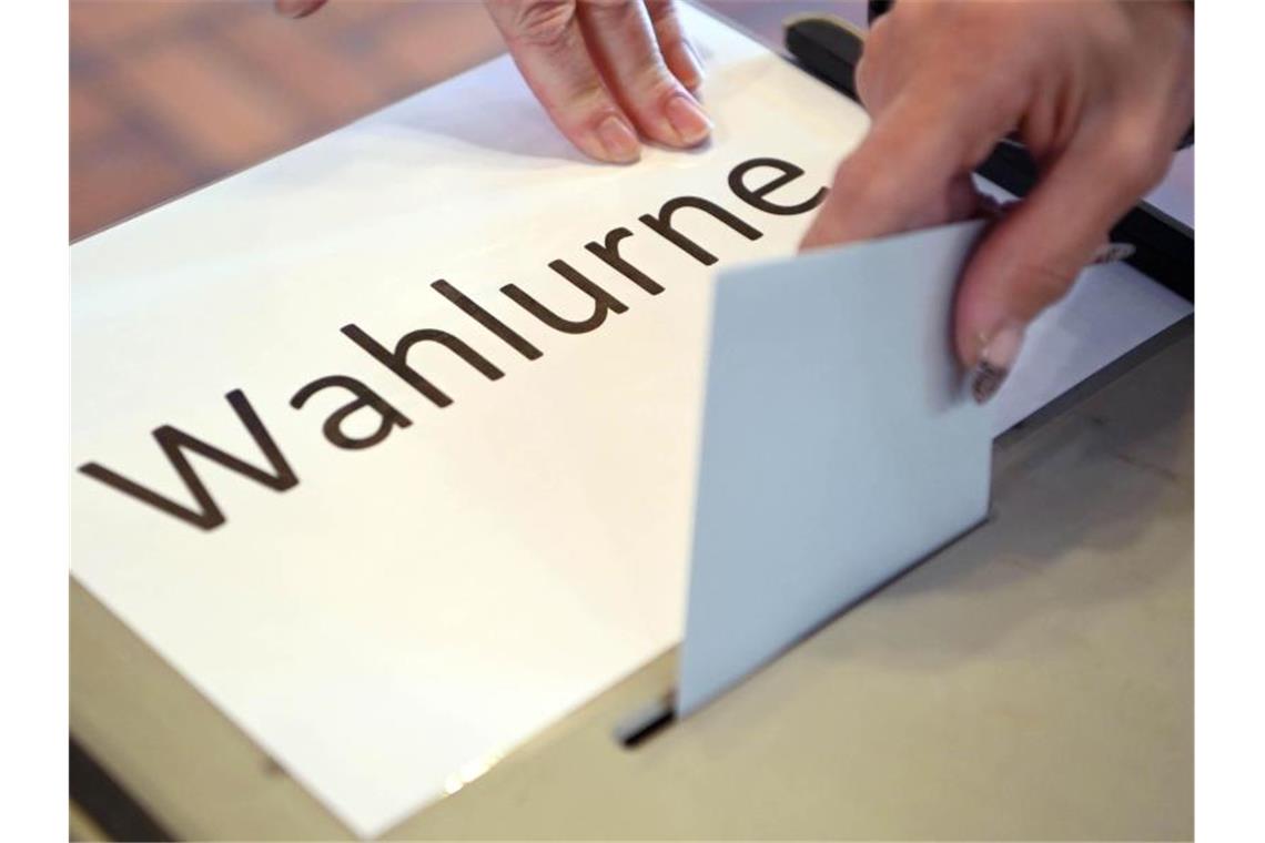 In einem Wahllokal wird ein Stimmzettel in eine Wahlurne geworfen. Foto: Uli Deck/dpa/Symbolbild