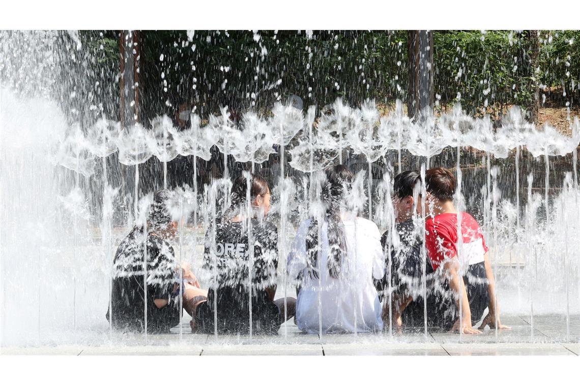 In Südkorea herrscht eine Hitzewelle. Um kühlen Kopf zu bewahren, erfrischen sich diese Schülerinnen und Schüler kurzerhand in einem Brunnen.