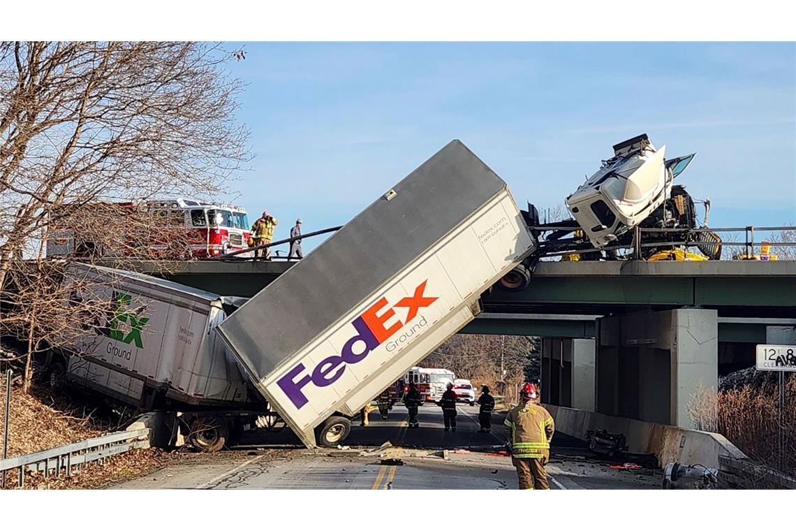 Interstate Richtung New York: Feuerwehrleute untersuchen die Unfallstelle, an der ein Lkw auf einer Brücke umgestürzt ist.
