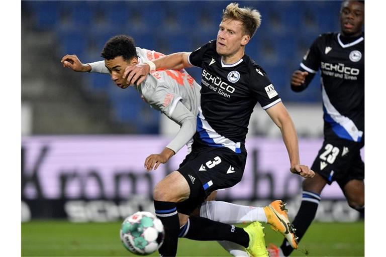 Jamal Musiala (l) von Bayern in Aktion gegen Brian Behrendt (M) von Bielefeld. Foto: Martin Meissner/AP-Pool/dpa