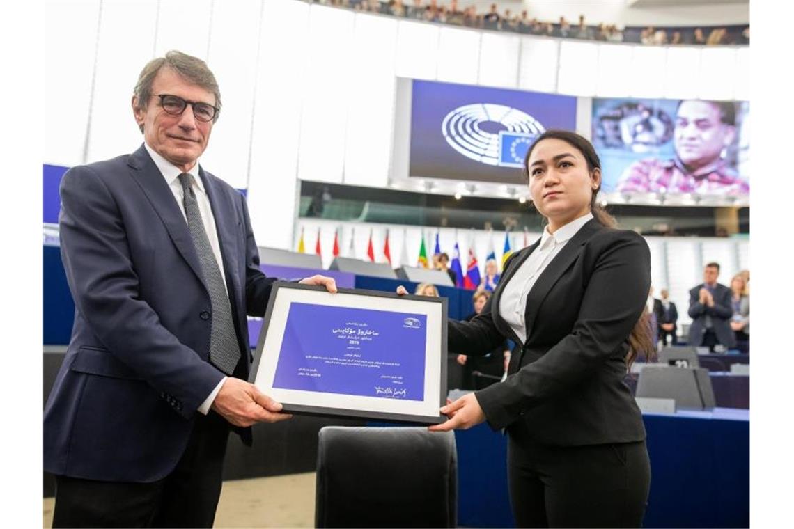 EU-Parlament vergibt Sacharow-Preis an inhaftierten Uiguren Jewher Ilham nimmt für ihren Vater den Sacharow-Preis aus den Händen des Präsidenten des Europäischen Parlaments, David Sassoli, entgegen. Im Hintergrund ist ein Foto von Ilham Tohti zu sehen. Foto: Philipp von Ditfurth/dpa