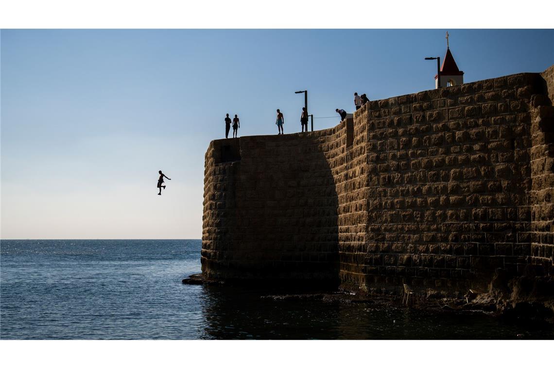 Jugendliche springen von der alten Stadtmauer von Akko in Israel ins Mittelmeer.