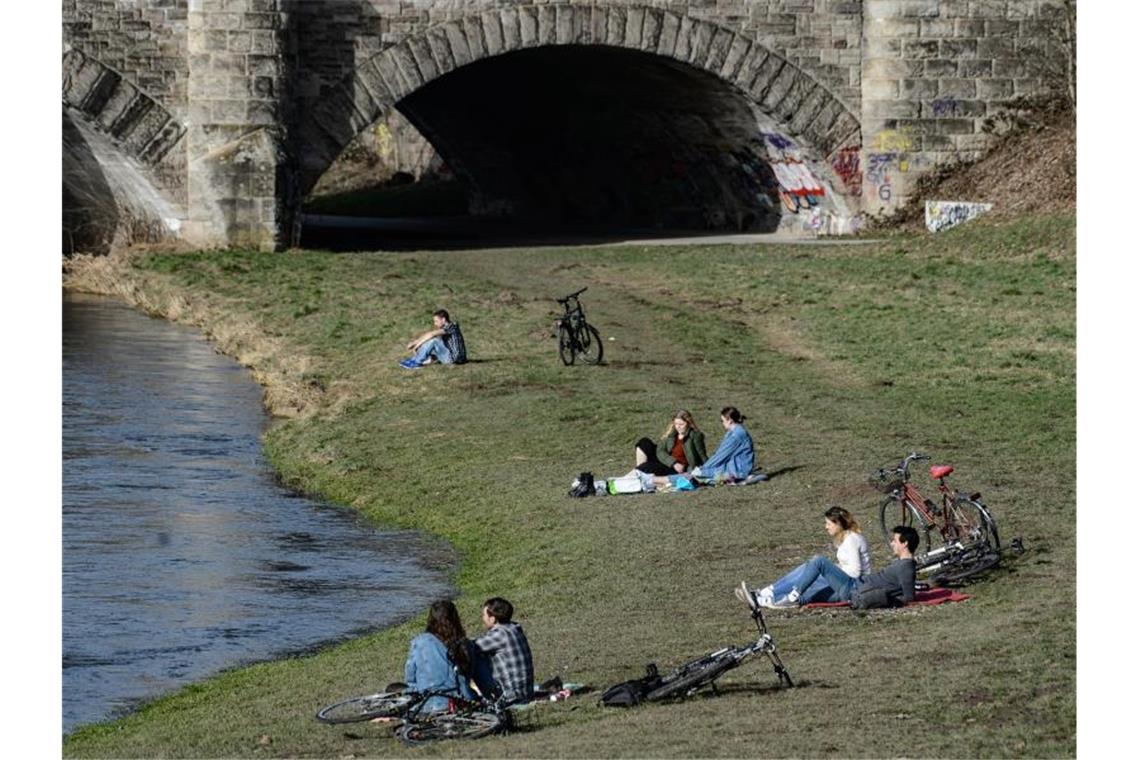 Frühlingsgefühle können bleiben: Temperaturen bis 21 Grad Junge Menschen genießen am Ufer der Leine in Göttingen das milde Wetter. Foto: Swen Pförtner/dpa