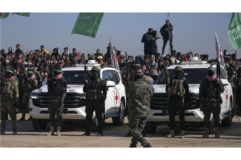 Kämpfer der Hamas und des Islamischen Dschihad beziehen Stellung vor Autos des Internationalen Roten Kreuzes, die auf die israelischen Geiseln warten.