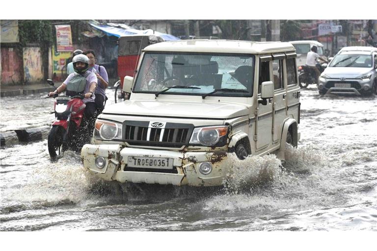 Kampf gegen Wassermassen: Pendler im indischen Guwahati fahren durch eine überschwemmte Straße nach starken Regenfällen.