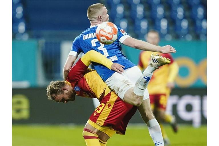 Karlsruhes Philipp Hofmann (l) und Darmstadts Thomas Isherwood haben den Ball aus dem Blick verloren. Foto: Uwe Anspach/dpa/Archivbild