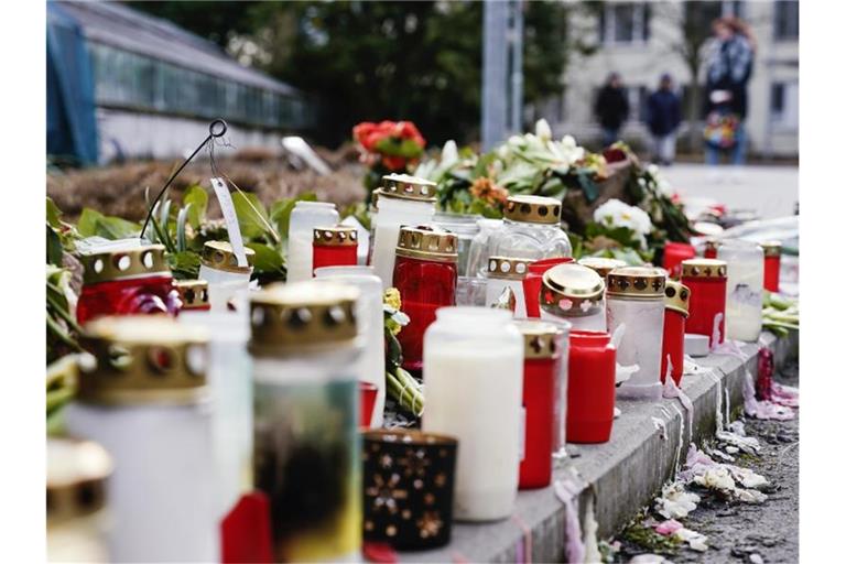 Kerzen und Blumen liegen vor einem Universitätsgebäude am Botanischen Garten. Foto: Uwe Anspach/dpa