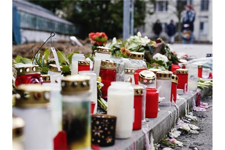 Kerzen und Blumen liegen vor einem Universitätsgebäude am Botanischen Garten. Foto: Uwe Anspach/dpa/Bildarchiv