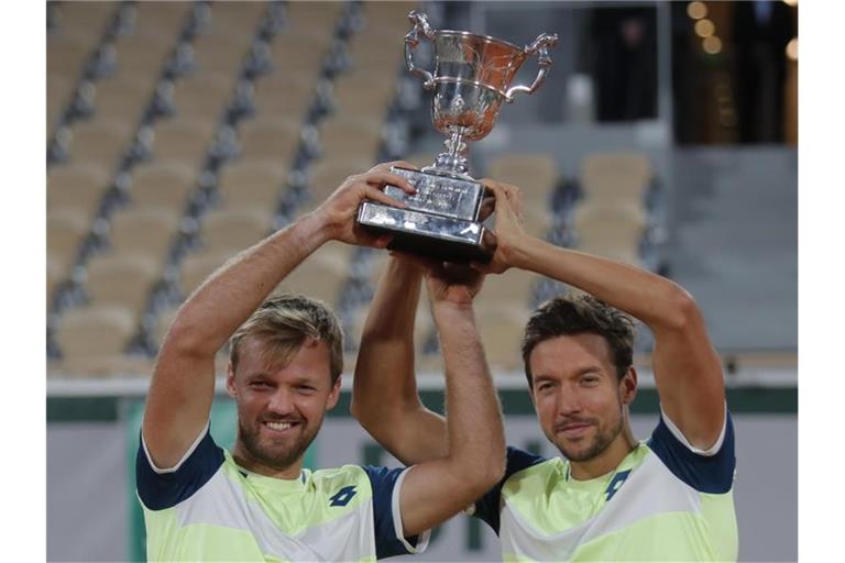 Kevin Krawietz (l) und Andreas Mies feiern mit der Trophäe den Finalsieg. Foto: Michel Euler/AP/dpa