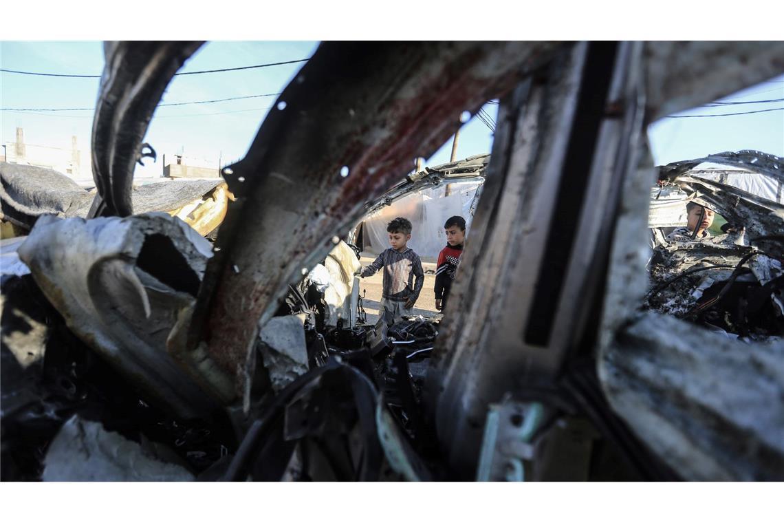Kinder in Rafah im Gazastreifen inspizieren ein komplett zerstörtes Auto nach einem israelischen Bombenangriff.