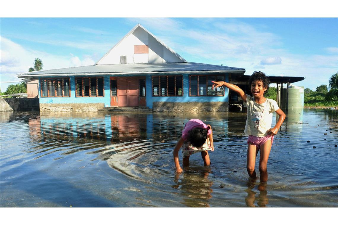 Kinder spielen auf einem vom Meerwasser überflutetem Platz in Funafuti, der Hauptstadt von Tuvalu.