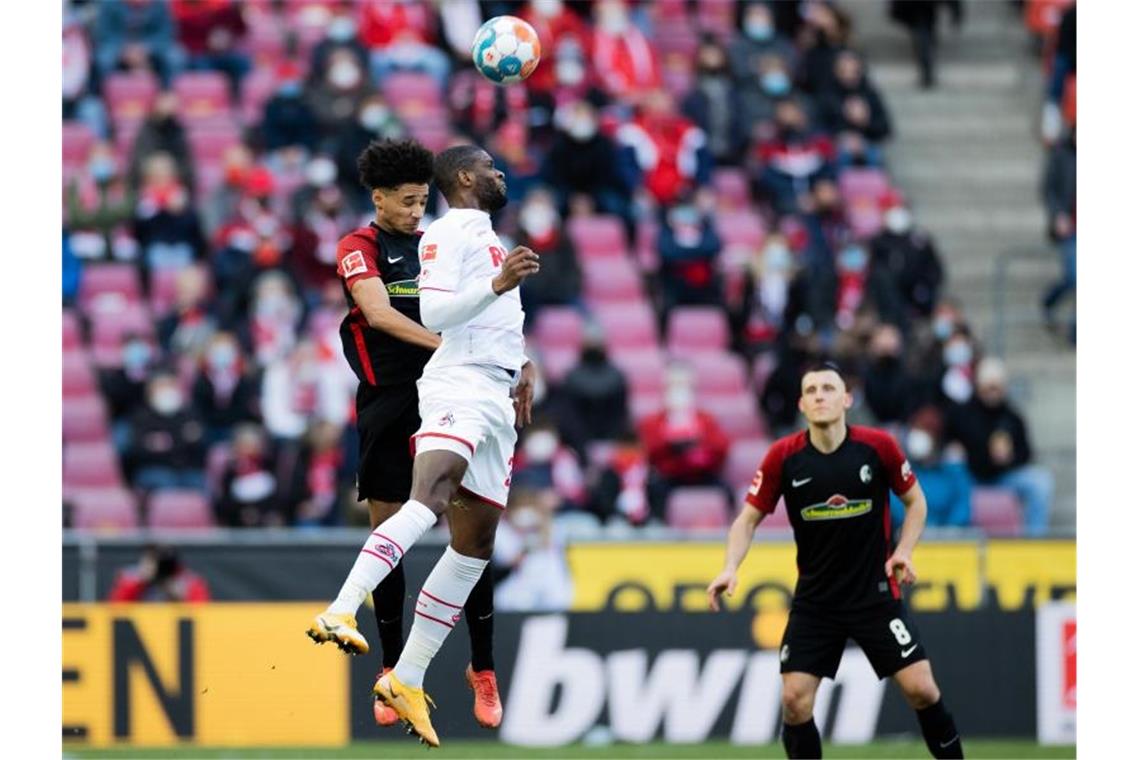 Kölns Anthony Modeste (M) und Freiburgs Kevin Schade versuchen an den Ball zu kommen. Foto: Rolf Vennenbernd/dpa