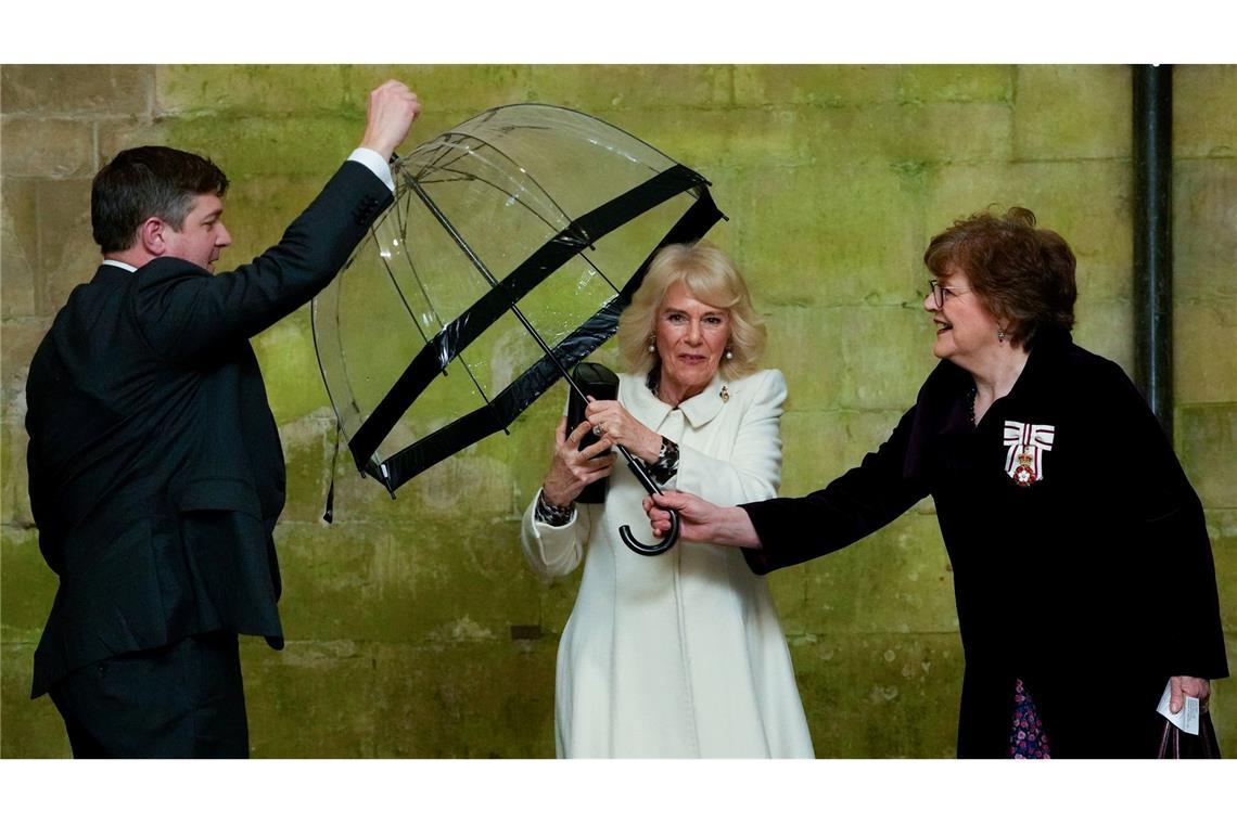 Königin Camilla reicht einem Adjutanten ihren Regenschirm, als sie zu einem musikalischen Abend in der Kathedrale von Salisbury eintrifft, um die Arbeit lokaler Wohltätigkeitsorganisationen zu feiern.