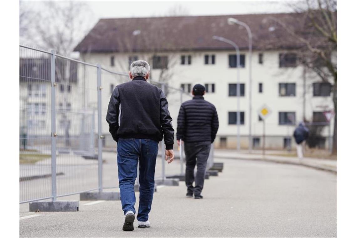 Südwesten bereitet sich auf deutlich mehr Flüchtlinge vor Männer gehen vor einer Unterkunft in der Landeserstaufnahmeeinrichtung auf einer Straße. Foto: Uwe Anspach/dpa
