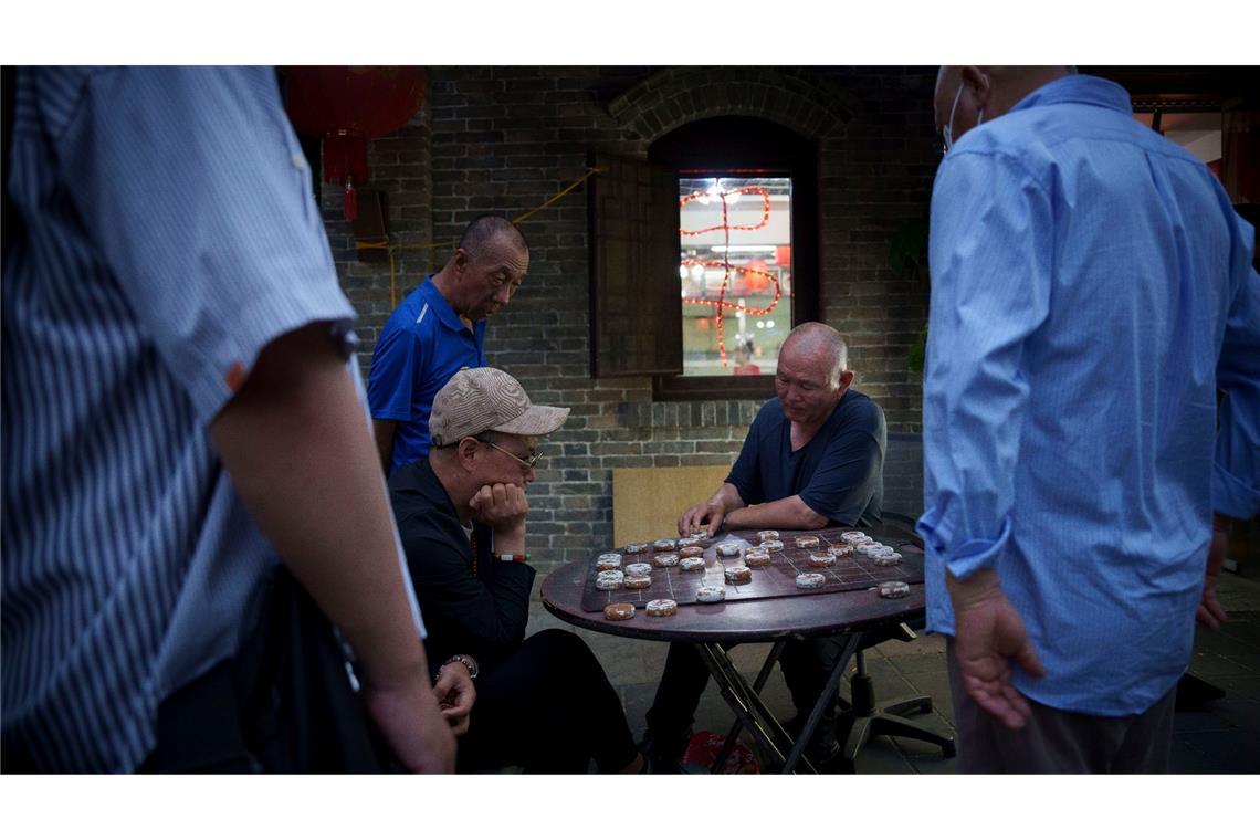 Männer spielen Schach entlang der Hauptstraße von Wudaoying Hutong in Peking.