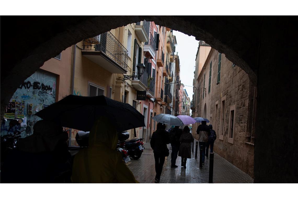 Mallorca: Menschen spazieren mit Regenschirmen in der Innenstadt von Palma