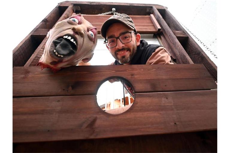 Marcel Lang steht an seinem Haus an einer nachgebauten Guillotine mit einem Halloween Totenkopf. Foto: Uli Deck/dpa