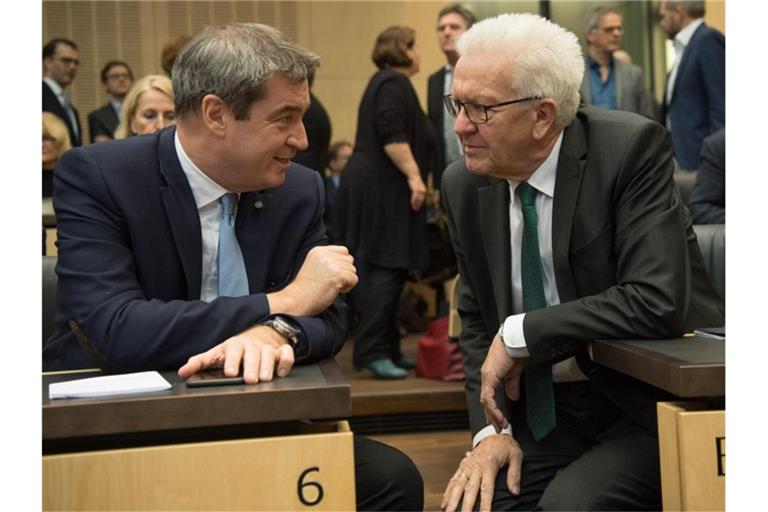 Markus Söder (l, CSU) und Winfried Kretschmann (Bündnis 90/Die Grünen) unterhalten sich im Bundesrat. Foto: Jörg Carstensen/dpa/Archivbild