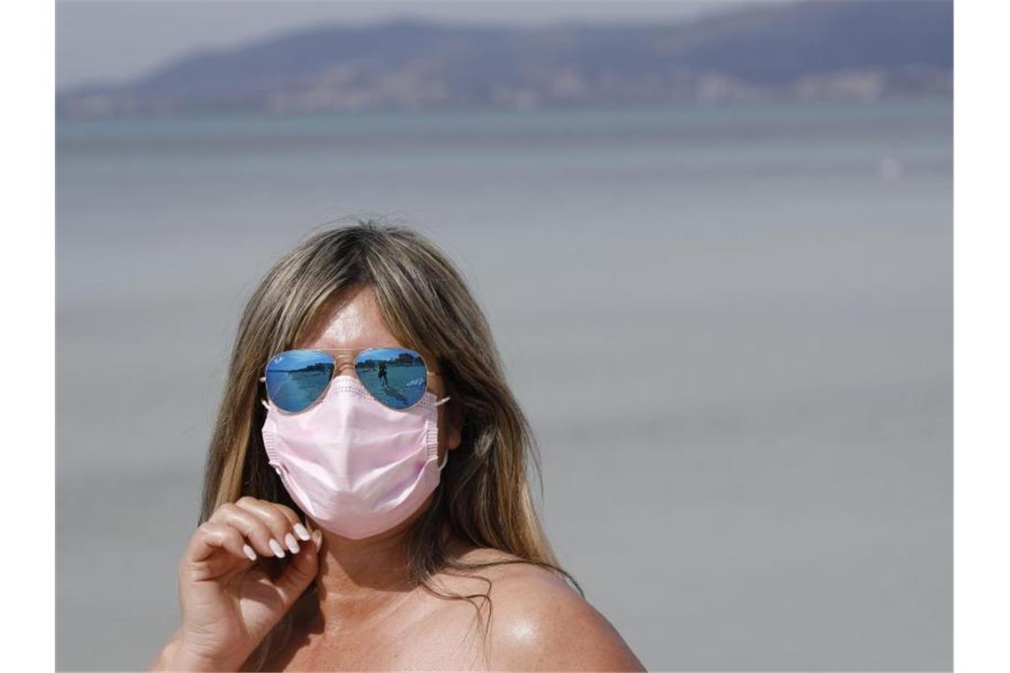 Medienbericht: Ganz Spanien soll Corona-Risikogebiet werden Maske am Strand: Auch 2021 steht der Sommerurlaub - wie hier auf Mallorca - ganz im Zeichen der Pandemie. Foto: Clara Margais/dpa