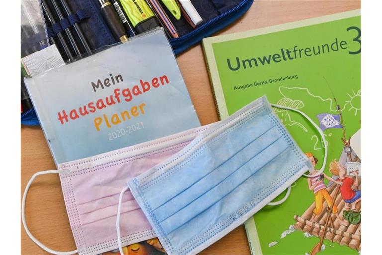 Masken liegen auf Arbeitsmaterialien eines Schülers. Foto: Patrick Pleul/dpa-Zentralbild/ZB/Symbolbild