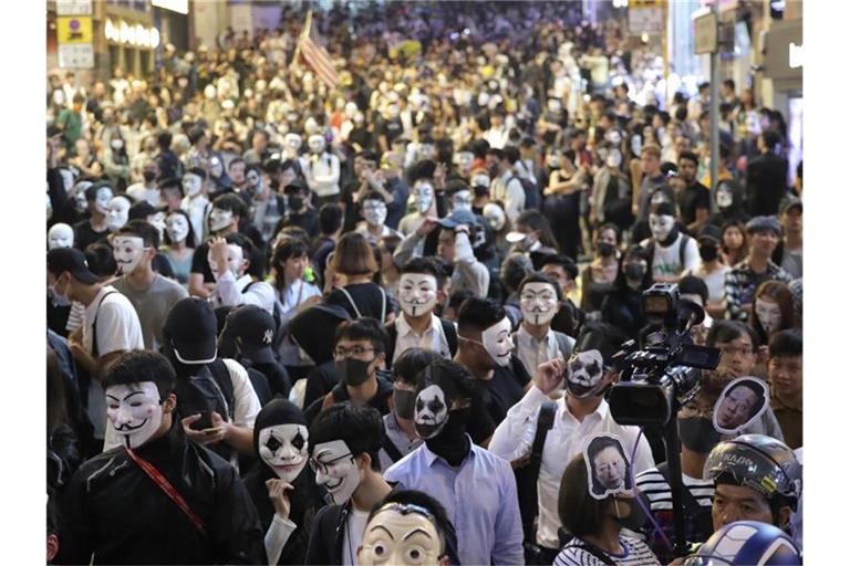 Maskierte Demonstranten versammeln sich auf einer Straße in Hongkong. Foto: Kin Cheung/AP/dpa