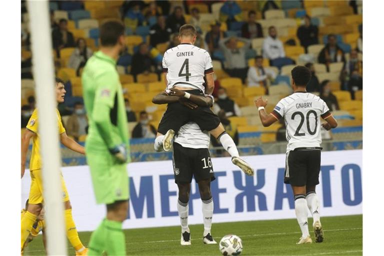 Matthias Ginter, Torschütze zum 1:0, wird von Mannschaftskamerad Antonio Rüdiger beim jubeln hochgehoben - Serge Gnabry kommt zum feiern dazu. Foto: Efrem Lukatsky/AP/dpa