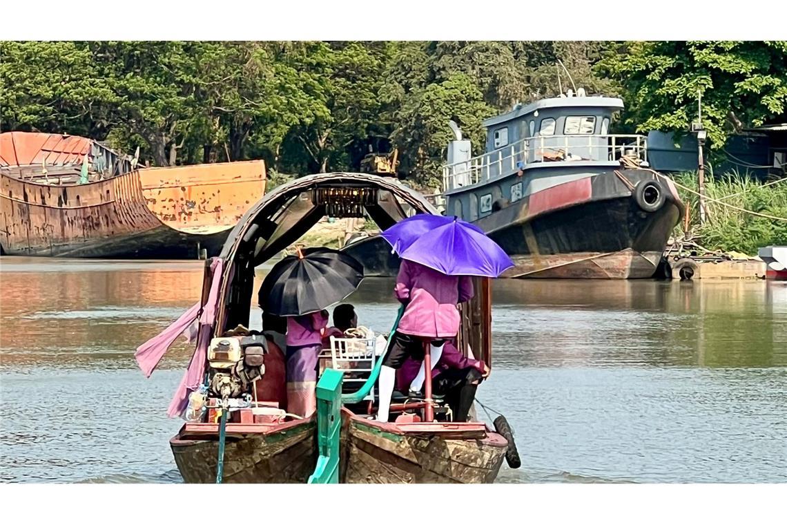 Menschen auf dem Pa Sak River schützen sich mit Sonnenschirmen vor der Sonneneinstrahlung und der extremen Hitze in Thailand.