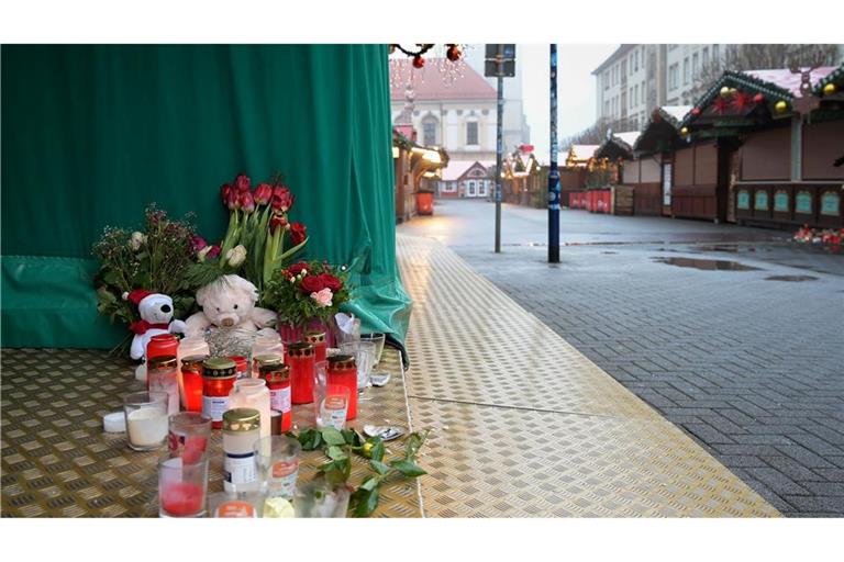 Menschen haben Blumen, Kerzen und Plüschtiere niedergelegt.