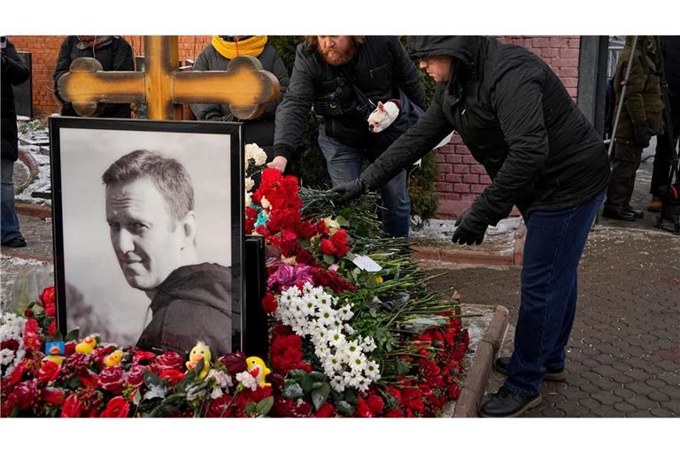 Menschen legen ein Jahr nach dem Tod des russischen Oppositionsführers Alexej Nawalny auf dem Borisowskoje-Friedhof in Moskau Blumen an seinem Grab nieder.