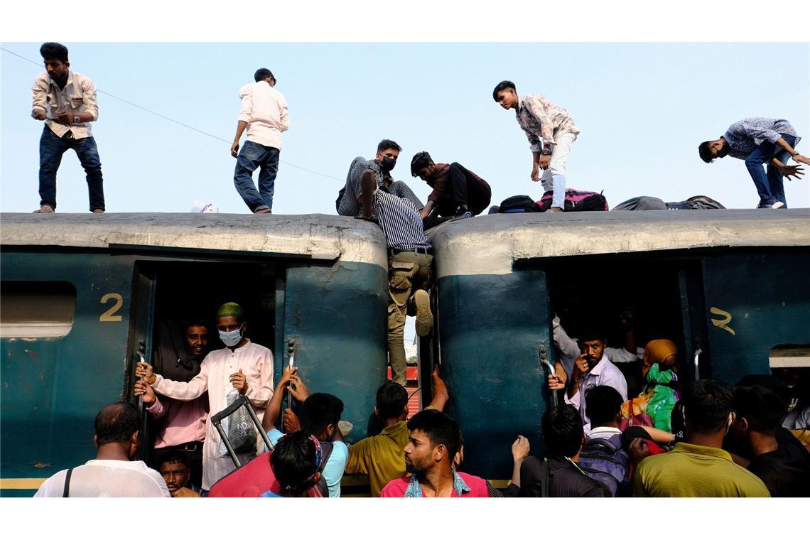 Menschen manövrieren auf dem Dach eines überfüllten Zuges in Dhaka in Bangladesch.