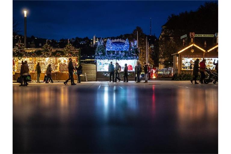 Menschen schlendern zur blauen Stunde auf dem Schlossplatz an Weihnachtsbuden vorbei. Foto: Christoph Schmidt/dpa/Archivbild