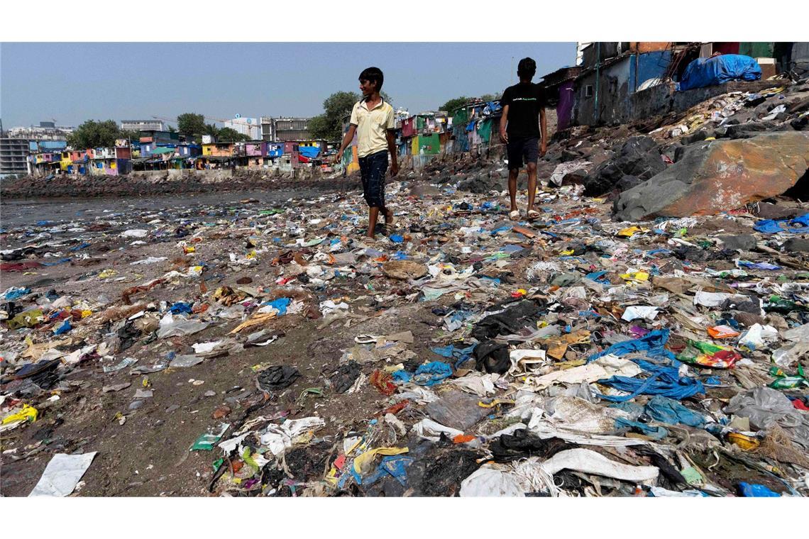 Menschen spazieren am Strand des Badhwar Park im indischen Mumbai an Plastikmüll vorbei. (Archivbild)