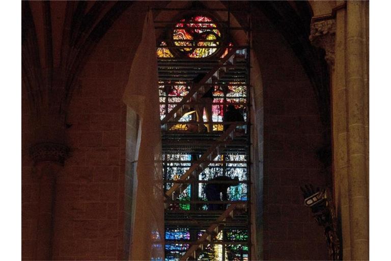 Menschen stehen im Ulmer Münster auf einem Gerüst vor einem Kirchenfenster. Foto: Stefan Puchner/dpa