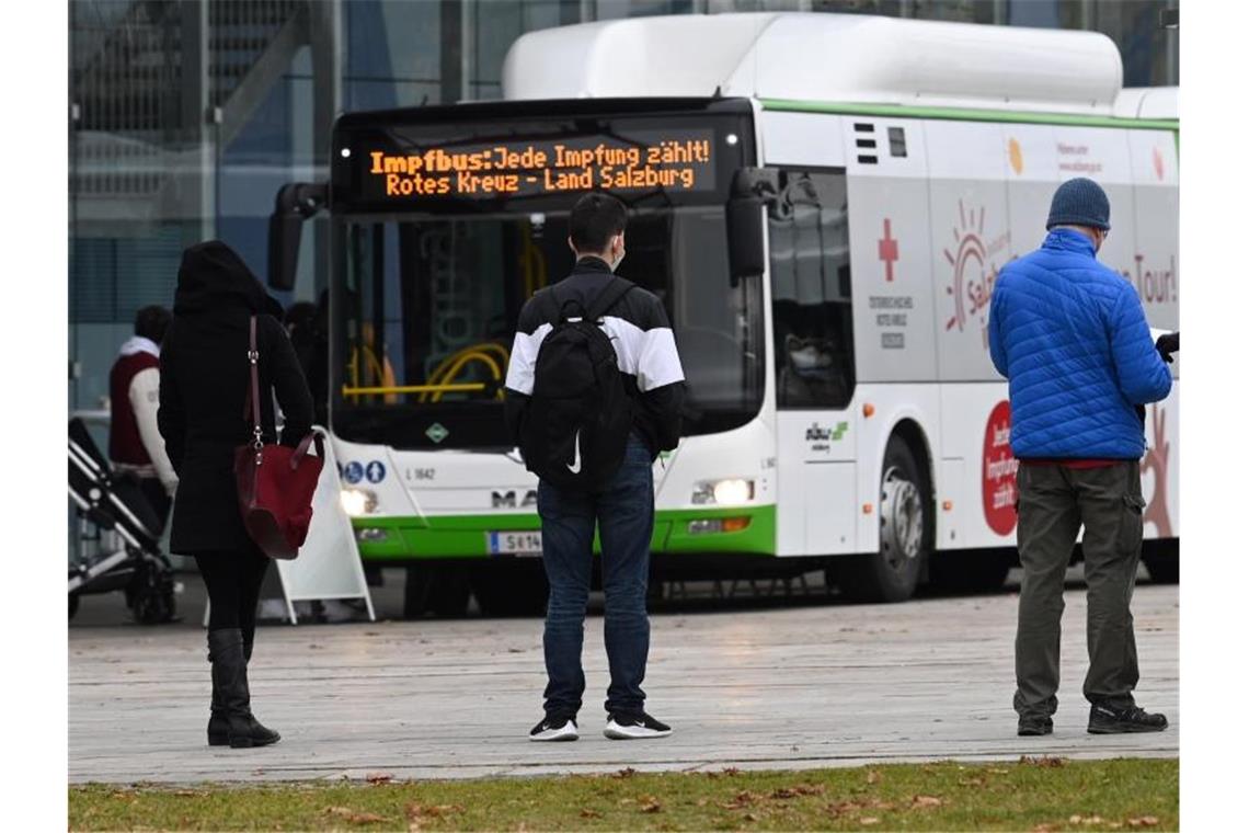 Österreich: Start des Lockdowns für Ungeimpfte Menschen stehen in Salzburg in einer Warteschlange vor einem Impfbus. Foto: Barbara Gindl/APA/dpa