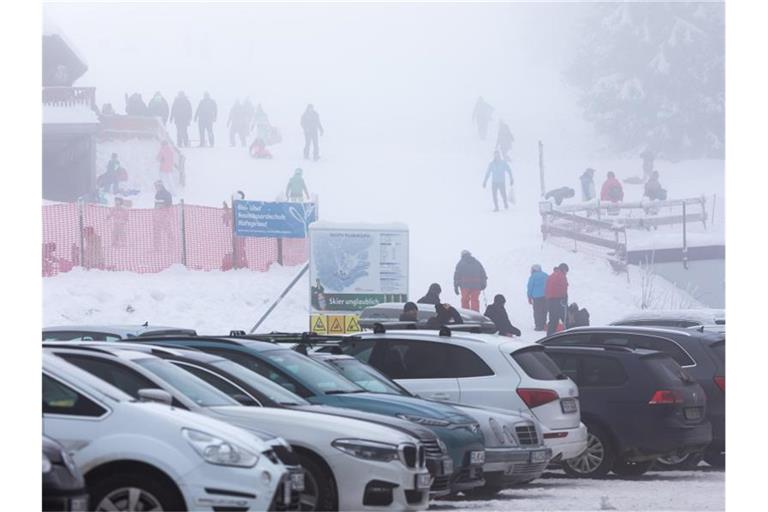 Menschen stehen neben einem Skilift am Haldenköpfle und vollen Parkplätzen. Foto: Philipp von Ditfurth/dpa/Archivbild