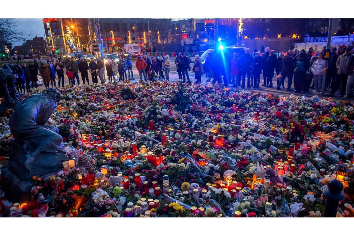 Menschen stehen vor der Johanniskirche in Magdeburg, wo ein Gedenkort eingerichtet und Blumen und Kerzen niedergelegt wurden.