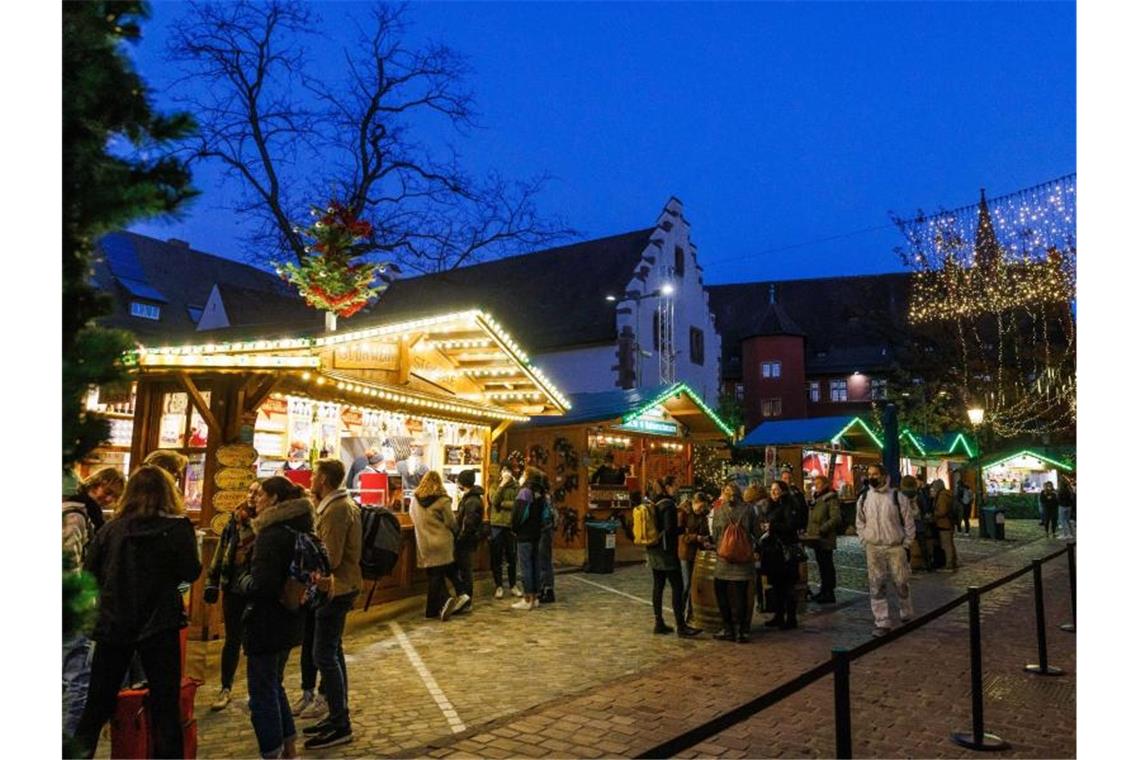 Menschen stehen vor Verkaufsständen auf dem Freiburger Weihnachtsmarkt. Foto: Philipp von Ditfurth/dpa/Archivbild